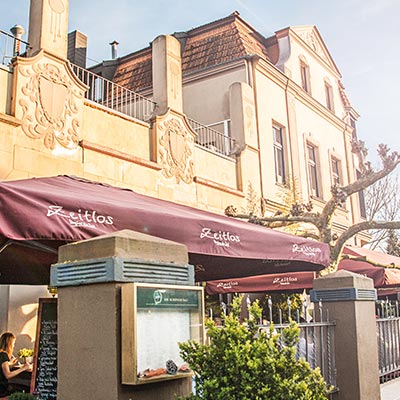 Sonnige Außenterrasse des Restaurant Zeitlos mit burgunderroten Markisen